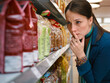 © Connect Images - Woman thoughtfully choosing bread in a supermarket aisle lined with colorful packages.   Germany