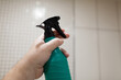 © mikeosphoto - Hand holding a green spray bottle with a black nozzle, ready for cleaning tasks, showcasing the importance of household maintenance and cleanliness in everyday life