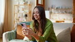 © stockbusters - Satisfied woman shopping online using mobile phone app sitting sofa closeup