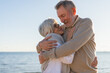 © Юлия Завалишина - Senior mature couple hugging enjoying outdoor recreation walking on beach. Old husband wife embracing with tenderness love enjoying sweet bonding. Grandmother grandfather together. Family moment love