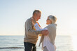 © Юлия Завалишина - Senior mature couple hugging enjoying outdoor recreation walking on beach. Old husband wife embracing with tenderness love enjoying sweet bonding. Grandmother grandfather together. Family moment love