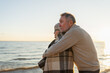 © Юлия Завалишина - Senior mature couple hugging enjoying outdoor recreation walking on beach. Old husband wife embracing with tenderness love enjoying sweet bonding. Grandmother grandfather together. Family moment love
