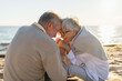 © Юлия Завалишина - Senior mature couple sitting on beach holding hands enjoying outdoor recreation. Old husband wife touching hands with tenderness love. Grandmother grandfather together. Family moment of love