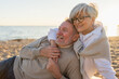 © Юлия Завалишина - Senior mature couple sitting on beach hugging enjoying outdoor recreation. Old husband wife embracing with tenderness love enjoying sweet bonding. Grandmother grandfather together. Family moment love