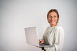 © Nenad - Professional businesswoman working on laptop, smiling confidently, grey backdrop
