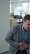 © soysuwan123 - A man in an office appears to be in discomfort, holding his stomach, suggesting a potential health issue or stress-related reaction.