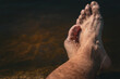 © Agus Buldo - Pies de un hombre relajándose en el agua, concepto de vacaciones y descanso.