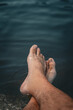 © Agus Buldo - Pies de un hombre relajándose en el agua, concepto de vacaciones y descanso.