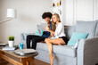 © ADDICTIVE STOCK - Happy couple using tablet on living room couch