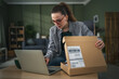 © Miljan Živković - Woman unpacking delivery with laptop showing disappointment