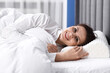 © New Africa - Smiling woman lying in bed with orthopedic pillow at home. Healthy posture