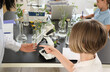 © Pixel-Shot - Female teacher showing glass with plant to pupil in Biology class at school, closeup