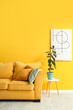 © Pixel-Shot - Interior of stylish living room with cozy sofa, picture and houseplant