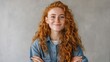 © mila103 - Woman with red hair is smiling and wearing a blue jacket. She is posing for a picture and has her arms crossed