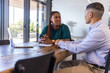 © wavebreak3 - Diverse coworkers in business attire discussing, viewing open laptop, papers at conference table