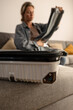 © blackday - Woman packing suitcase at home, close-up of hands organizing travel essentials.