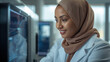 © siraphol - Smiling scientist in hijab working with laboratory equipment, focused and confident