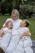 © Асель Иржанова - Happy mother with two children in the park. Mother with son and daughter sitting on the grass.