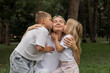 © Асель Иржанова - A happy mother with two children. A little son and daughter kissing their mother. The concept of happy motherhood and family support.