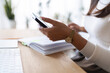 © Studio Marmellata - A person wearing a watch uses a smartphone while sitting at a desk with a notebook and keyboard.