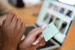 © Studio Marmellata - A person holds a payment card in front of a laptop screen, engaging in online shopping or a digital transaction.