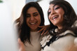 © Studio Marmellata - Two young women share a moment of laughter and joy, their faces illuminated by a bright light, conveying happiness and connection.