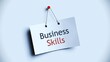 © skakter24 - White paper sign with 'Business Skills' text, one word blue and one word red, pinned to a light blue wall with a red thumbtack