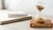 © AslamAG - Hourglass beside a notebook, representing time management