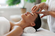 © Home-stock - Facial Relaxation. Young woman receiving head massage, enjoying beauty treatment while masseur massaging lady's forehead