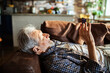 © Geber86 - Senior man relaxing on couch at home using smartphone