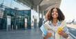 © insta_photos - Happy foreign college student holding smartphone standing in airport. Smiling African American girl applying international university studying abroad using phone advertising exchange program. Banner