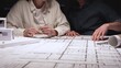 © rogerphoto - Architects and engineers collaborating on a new building project, planning structural details and design concepts using blueprints and a scaled architectural model on a desktop