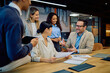 © we.bond.creations - Group of diverse business people engaging in a lively discussion during a team meeting in a modern office boardroom