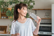 © buritora - Asian woman hydrating with bottled mineral water after training at home