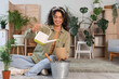 © Pixel-Shot - Young African-American woman pouring water into plant pot at home