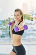 © Laflor2000/peopleimages.com - Portrait, home and happy woman with fitness, dumbbells and exercise with confidence. Smile, equipment and healthy person with routine, training and wellness with practice, cardio workout and energy