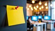 © amanullahkhan - Yellow sticky note pinned on wall with blurred office background