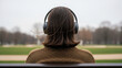 © Yulia - Man with closed eyes listening to audiobook on headphones, sitting on park bench with serene landscape, wearing brown sweater, overcast sky