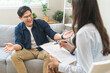 © KMPZZZ - Psychology, depression. smile asian young male, man patient mental sitting on couch, explained symptom with psychologist, psychiatrist while doctor woman taking notes at clinic. Encouraging, therapy.