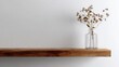 © thg - Minimalist Home Decor: Transparent Glass Vase on Wooden Shelf Against White Matte Wall.
