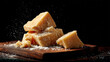© Sabana - Chunks of parmesan cheese on a wooden cutting board with powdered cheese