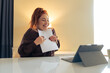 © Lomb - A happy woman at home hugs a document while smiling at a tablet, expressing joy, relief and positive online news