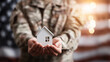 © Bonsales - Soldier hands holding small house model, symbolizing veteran home loan, real estate investment, and military family support under an American flag