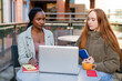© Iryna - Friends work together at an outdoor cafe using a laptop and taking notes during the daytime