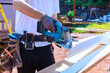 © ungvar - Work on construction vinyl siding with saw in hands at outdoor site with tools on belt