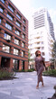 © ekaterinabyuksel - Young woman resting and relaxing while walking on city street in new eco-friendly residential complex. Relaxation and stress-free concept.
