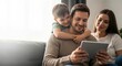© ArtFocus Studio - Happy young family with a small son sitting on a sofa and using a digital tablet together in a bright living room at home.