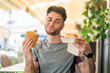 © luismolinero - Young handsome man holding a burger and fried chips