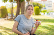 © luismolinero - Young blonde woman holding a bowl of fruit at outdoors