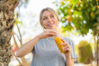 © luismolinero - Young blonde woman holding an orange juice at outdoors